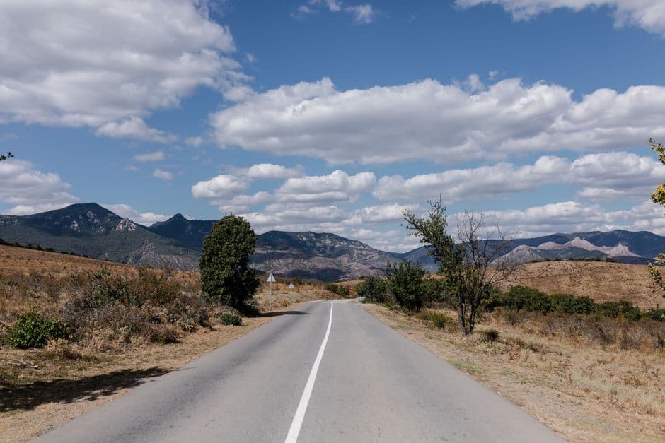 A serene road stretches through the picturesque Crimean Mountains under a clear sky.